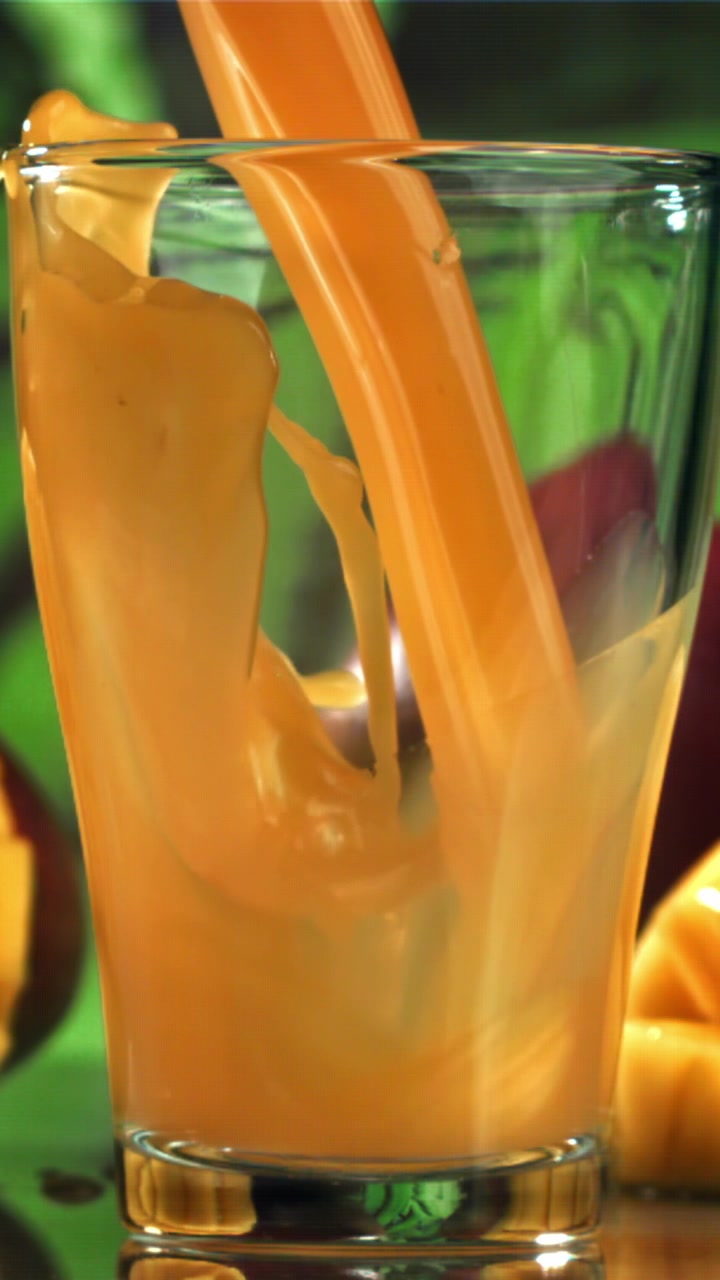 Succo di mango fresco versato in un bicchiere al rallentatore