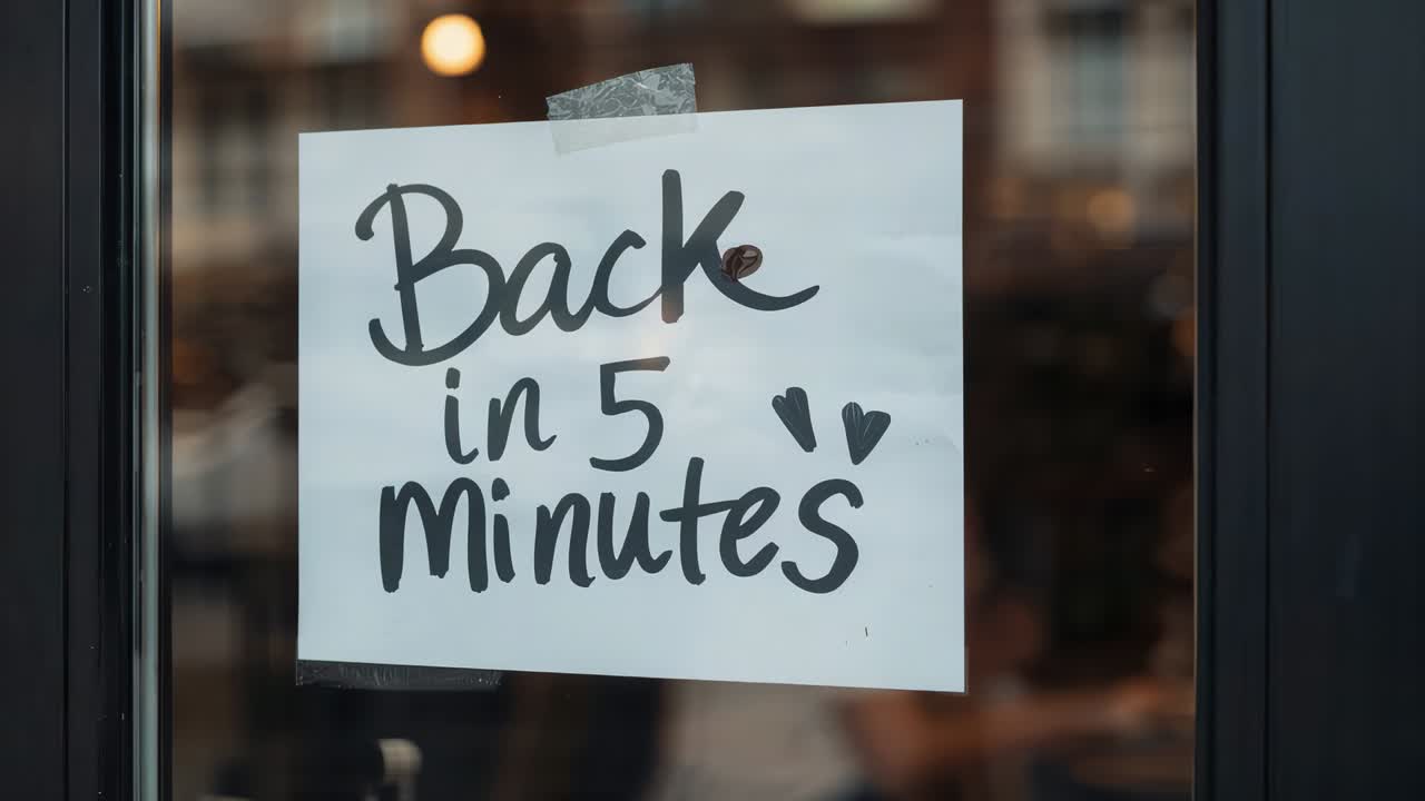 Personale sætter 'Tilbage om 5 minutter'-skilt på glasdøren, mens kunderne går indenfor i pausen