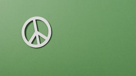 close up of white peace sign and copy space on green background