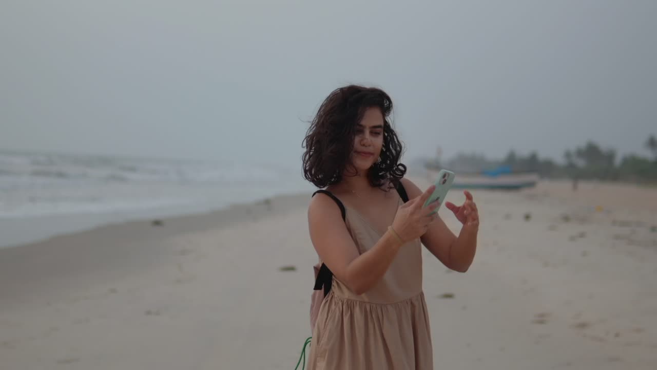 Young Indian woman is taking a selfie on the beach ijn India