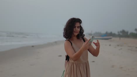 young indian woman is taking a selfie on the beach ijn india