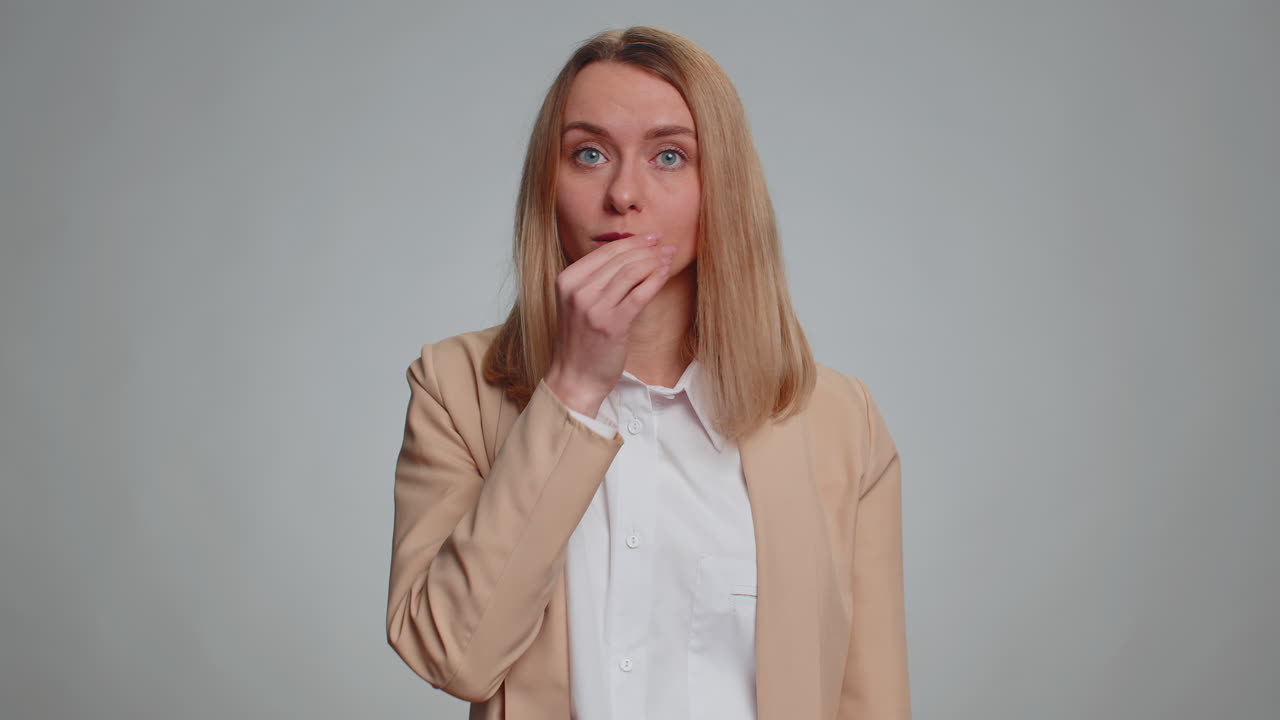 Business woman presses index finger to lips makes silence sign shh be quiet please keep my secret