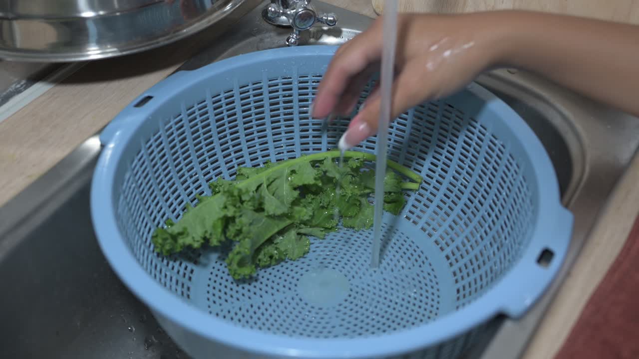 Close-up shot of fresh raw organic kale leaves washed and prepared at home kitchen during night