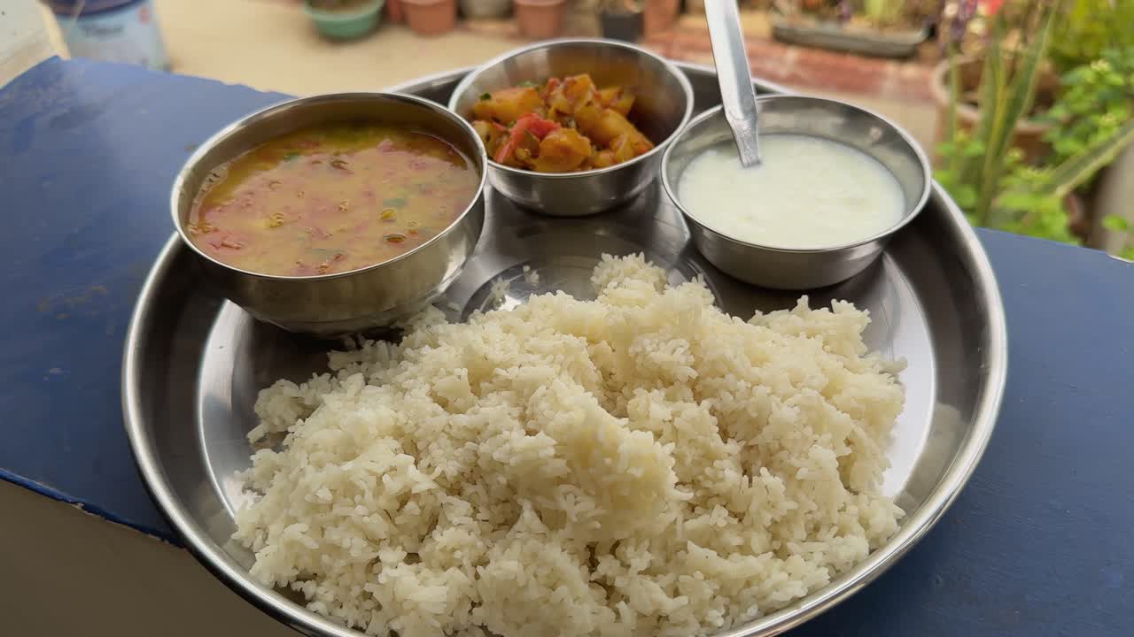 closeup of an everyday veg thali meal in indian home, camera circling around an indian veg thali with dal, rice, veggies and a bowl of yogurt