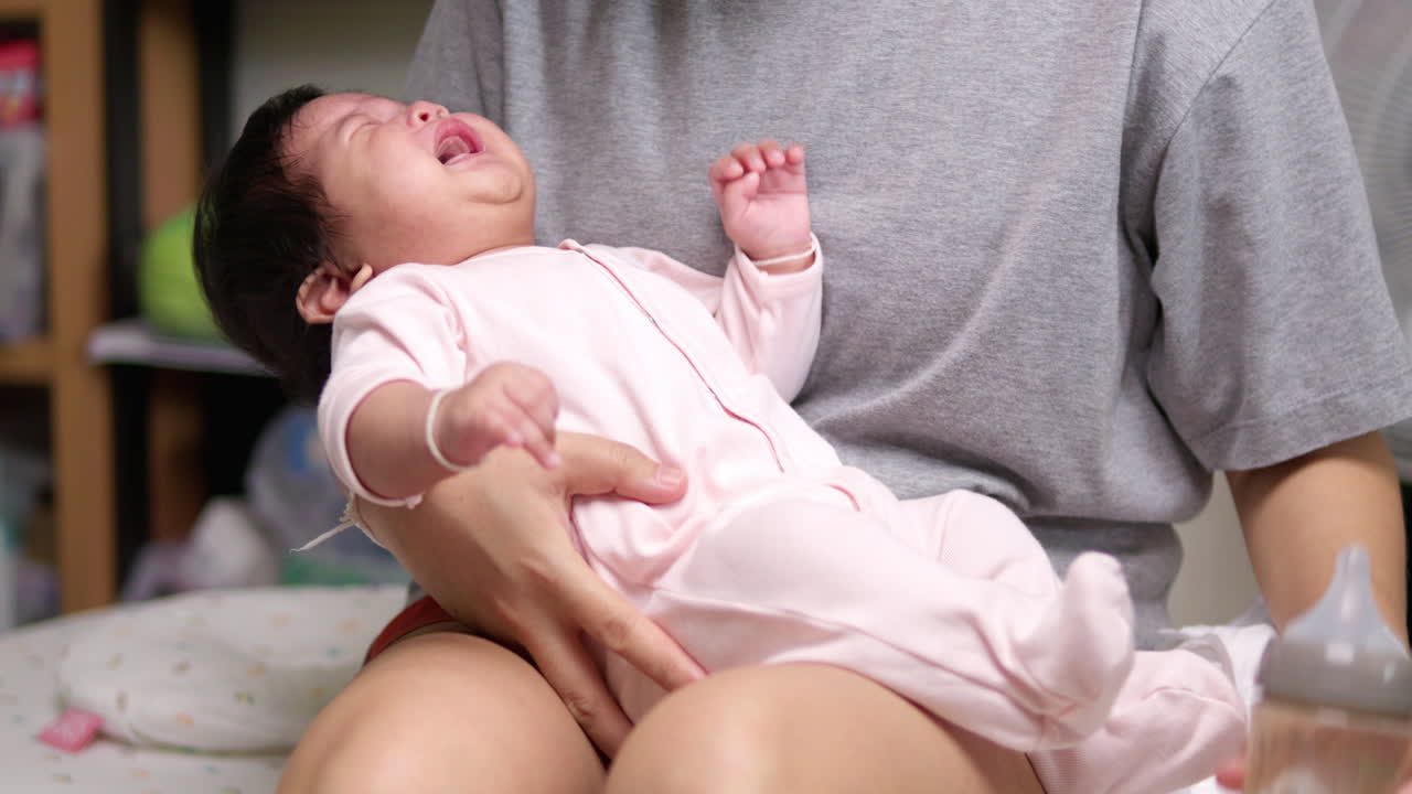 주린 신생아 가 모유 로 가득 찬 식료품 병 을 사용 하여 어머니 에게 먹이 를 달라고 울고 있다