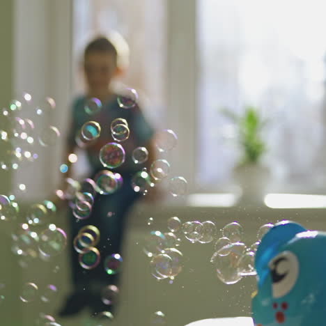 colorful circle bubbles flying in the room on the blur background with a boy. special device for creating soap bubbles on the table. soap bubbles show inside the room.
