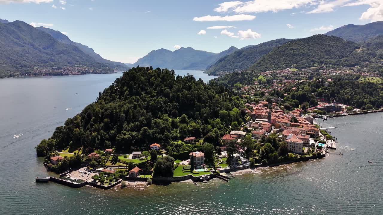 Aerial view of Bellagio on Lago di Como featuring a forested peninsula, waterfront villas, clustered village rooftops and expansive mountain scenery surrounding the calm lake under bright daylight