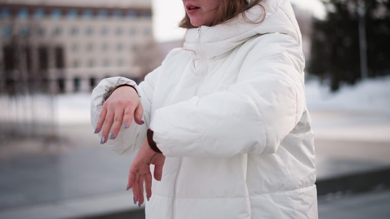Creative performing expressive hand dance outdoors wearing puffer jacket under winter sky with snow backdrop capturing dynamic motion energy through rhythmic gesture in urban park scene
