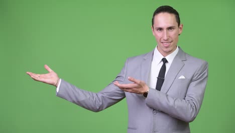 young happy handsome businessman showing something