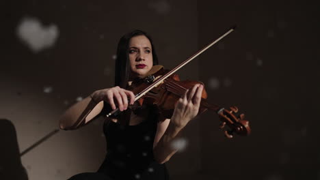 woman playing violin in dark studio