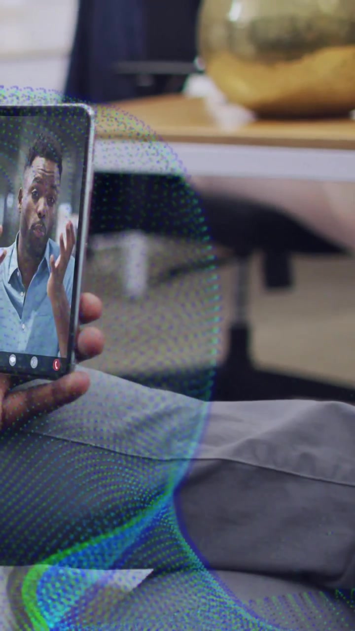 Video verticale: Una persona tiene fermo il telefono mentre un collega parla, gesticolando, mentre una rete verde acqua scorre, tecnologia.