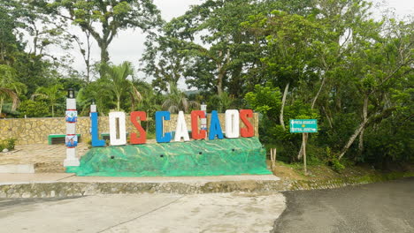 dolly in towards colorful los cacaos town sign, dominican republic, day