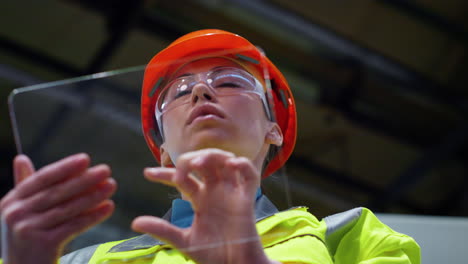 woman specialist working project on transparent tablet computer at factory.