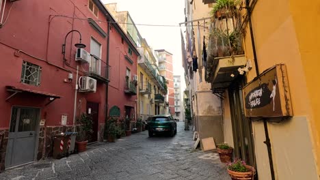 a car navigates a narrow street in naples