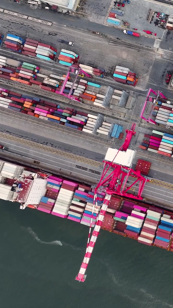 The operations at a container terminal where shipping containers are loaded and unloaded from cargo ships. The terminal handles global shipping and international trade.