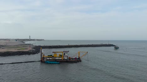 Aerial-flyover-shot-of-a-dredger-boat-used-for-digging-the-land-near-Pondicherry-harbor,-shot-with-a-drone-in-4k