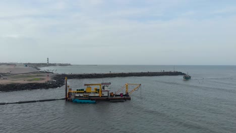 aerial flyover shot of a dredger boat used for digging the land near pondicherry harbor, shot with a drone in 4k