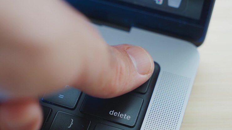 Person's thumb pressing on fingerprint scanner on laptop computer to access system or to confirm operation. Identifying user by clicking on key with ID reader for thumbprint. Close up in office desk