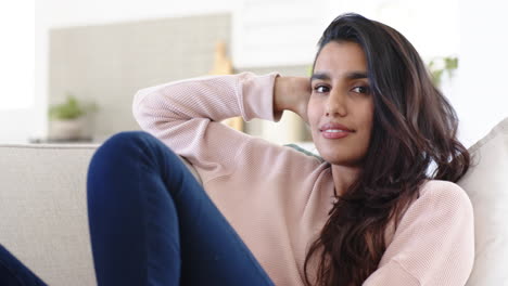 relaxing at home, indian woman smiling in cozy sweater on sofa
