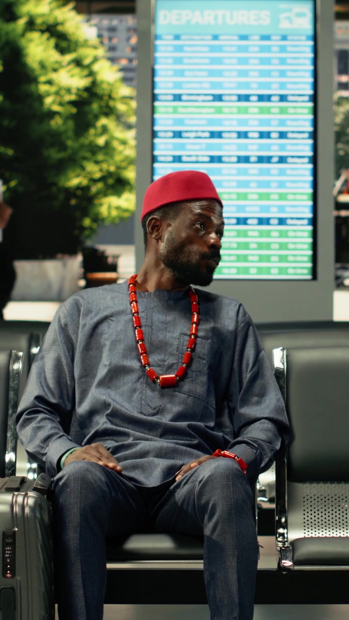 Man in african traditional clothes sitting in bus station for long-haul journey