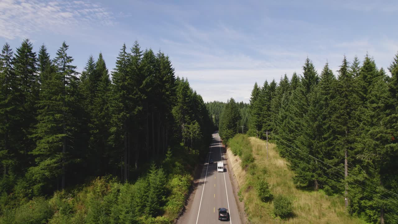 Mesmerizing drone shot overlooking Pacific Northwest highway cars, revealing an expansive sea of evergreen trees stretching to the horizon. Perfect for nature, travel, or adventure scenes.