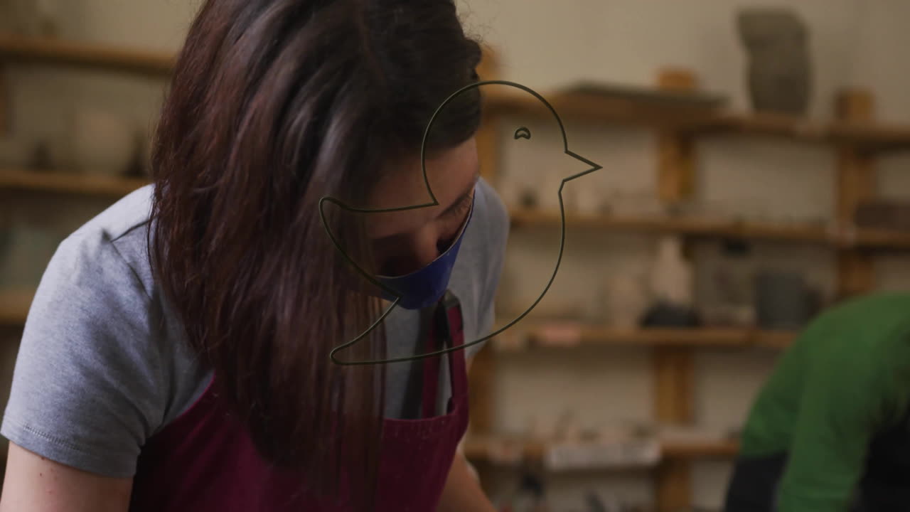 Person working in pottery studio with glowing bird animation overlay