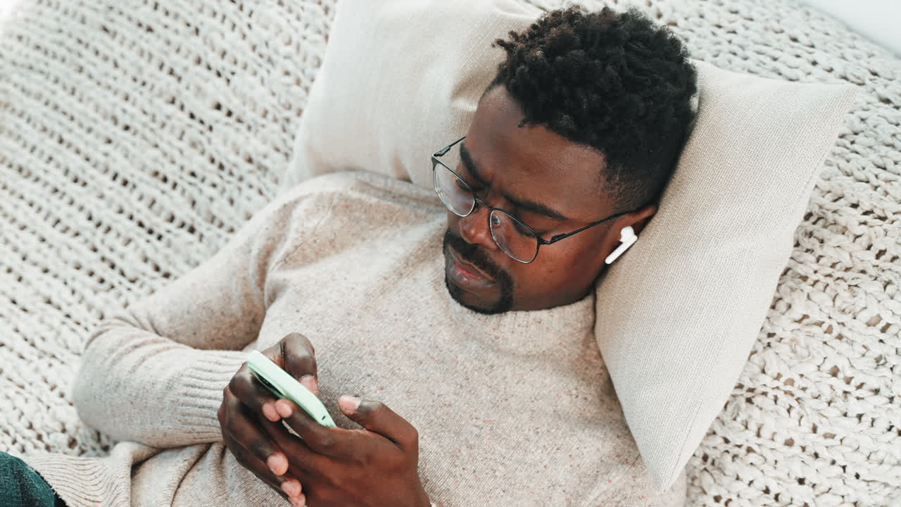 Man Relaxing on Couch with Smartphone