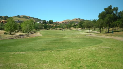 mansions overlooking lush golf course as golfers walk to next tee