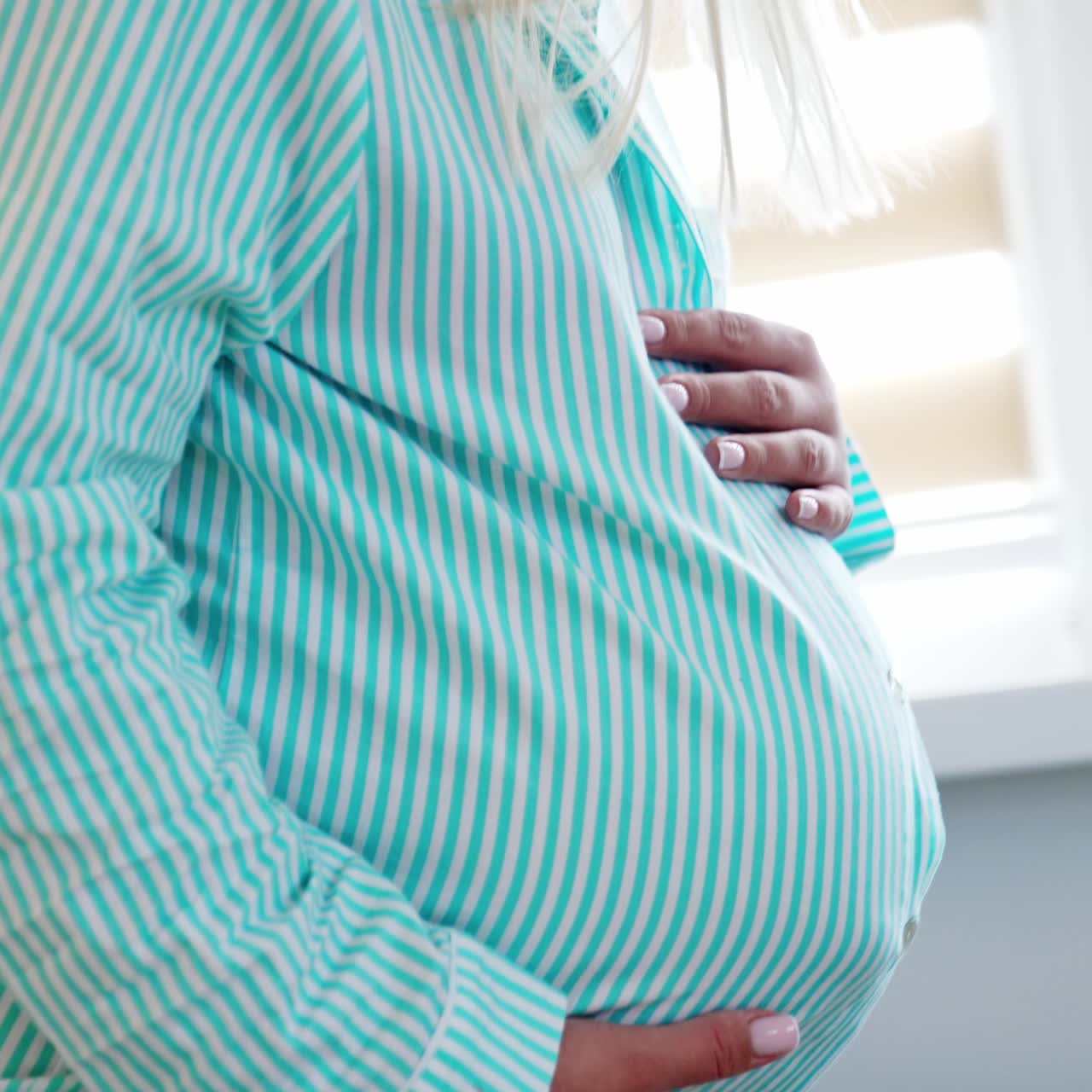 Unrecognized pregnant lady stroking big belly. Male hands touching the abdomen. Close up