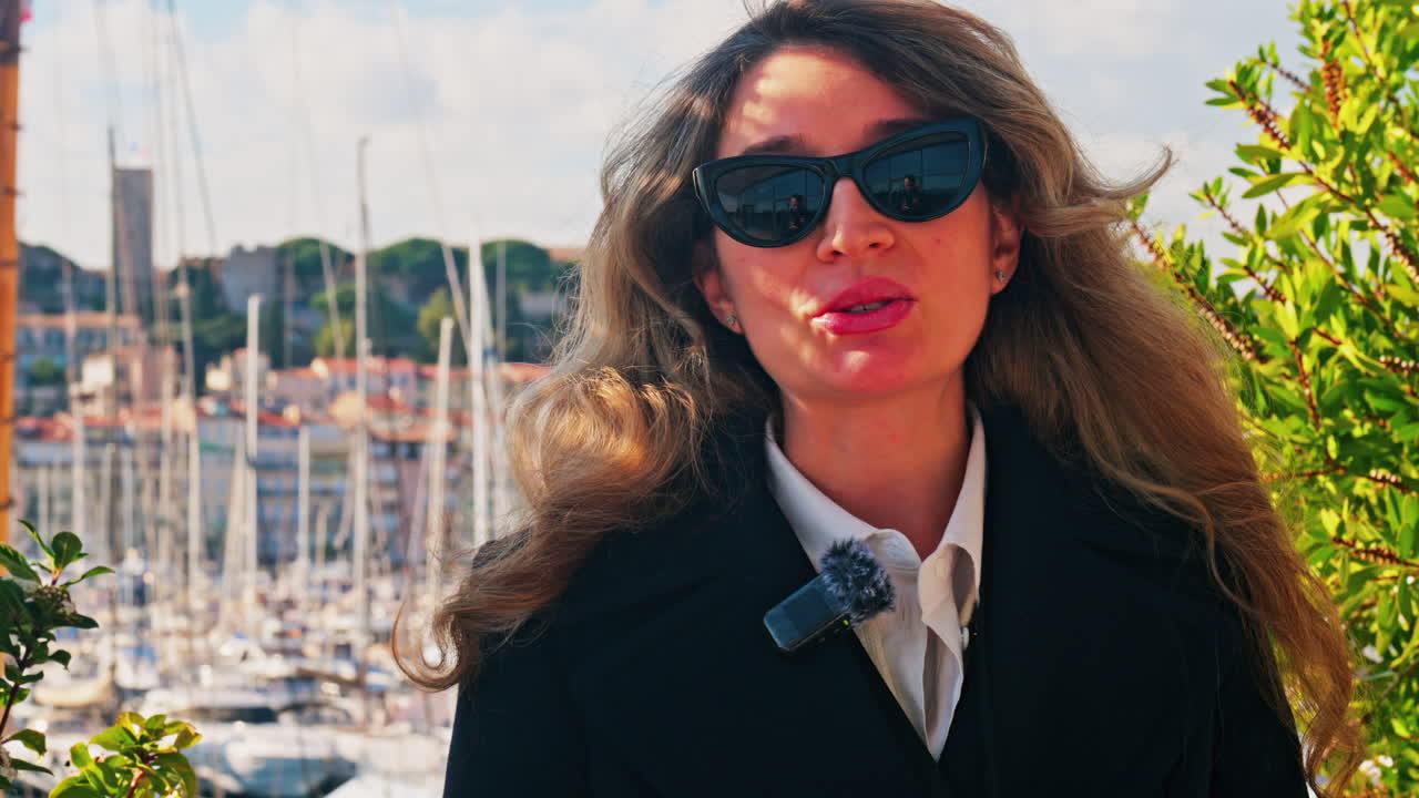 Woman wearing sunglasses talking in front of boats docked in the Pierre Canto Port in Cannes, France