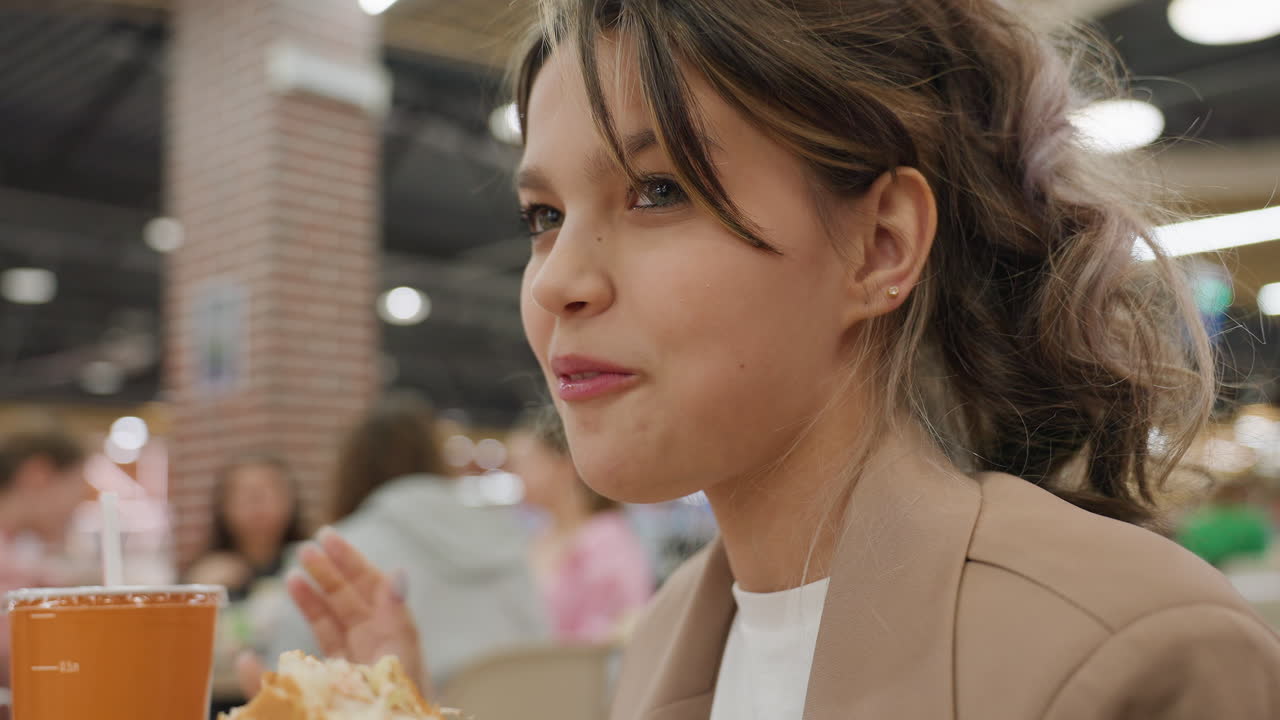 패스트푸드를 먹으며 휴식을 취하는 행복한 여성, 쇼핑몰 푸드 코트의 활기찬 분위기 속에서 햄버거와 탄산음료를 즐기며 즐거운 시간을 보내는 여성 고객, 북적거리는 쇼핑몰 푸드 코트에서 행복하게 식사를 즐기는 여성