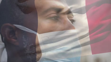 Animation-of-flag-of-france-waving-over-man-wearing-face-mask-during-covid-19-pandemic