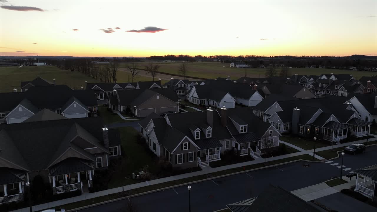 Luxury two-story homes in rural area of american town. Sunset time during winter season. Modern large houses in quiet neighborhood of USA. Descend drone wide shot.