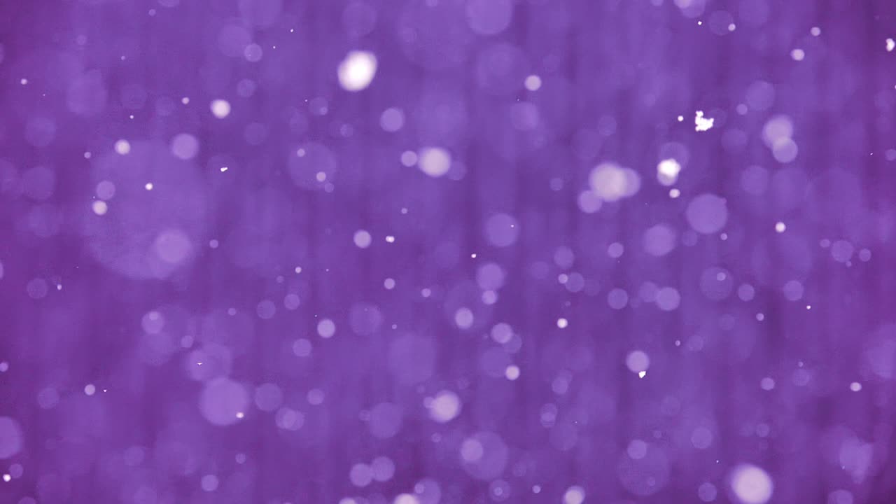 Snowflakes gently fall in slow motion over vivid purple textured striped surface