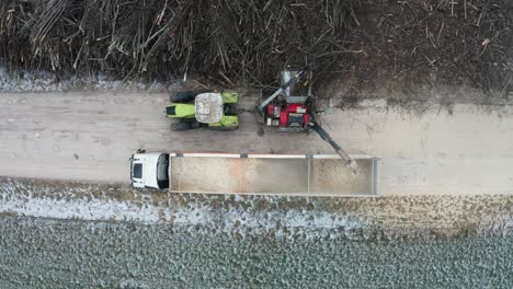 aerial static top down view of wood chipper shred wood from pile of branches