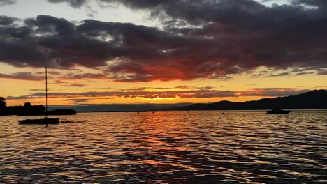 Toma-De-Puesta-De-Sol-Sobre-La-Montaña-Con-Ondas-De-Agua-Del-Lago-En-Primer-Plano-En-Las-Grangettes,-Suiza-Durante-La-Noche