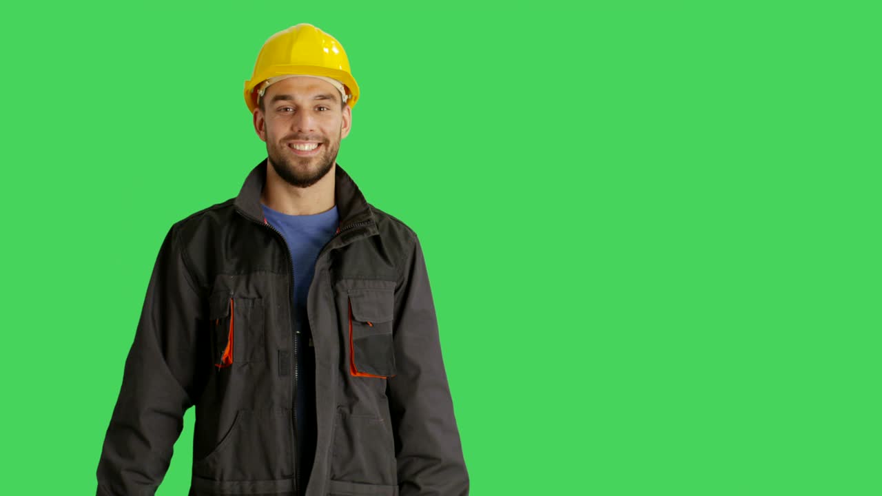 medio disparo de un trabajador sonriente con sombrero duro haciendo gestos de presentación. el fondo es pantalla verde.