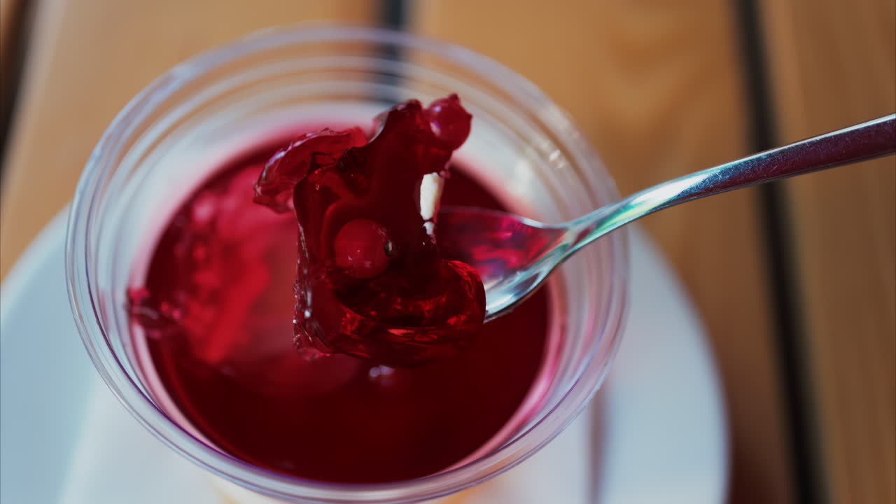 Close up of a bright layered jelly dessert in a clear cup on a wooden table