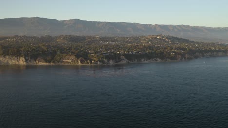 drone flies over pacific ocean toward california coast on summer evening