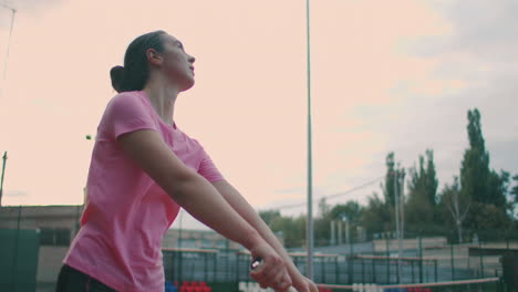 slow motion of woman making tennis serve. slow motion: section of woman bouncing ball on tennis court. athlete serves the tennis ball. young woman is hitting the ball with her tennis racket at sunset