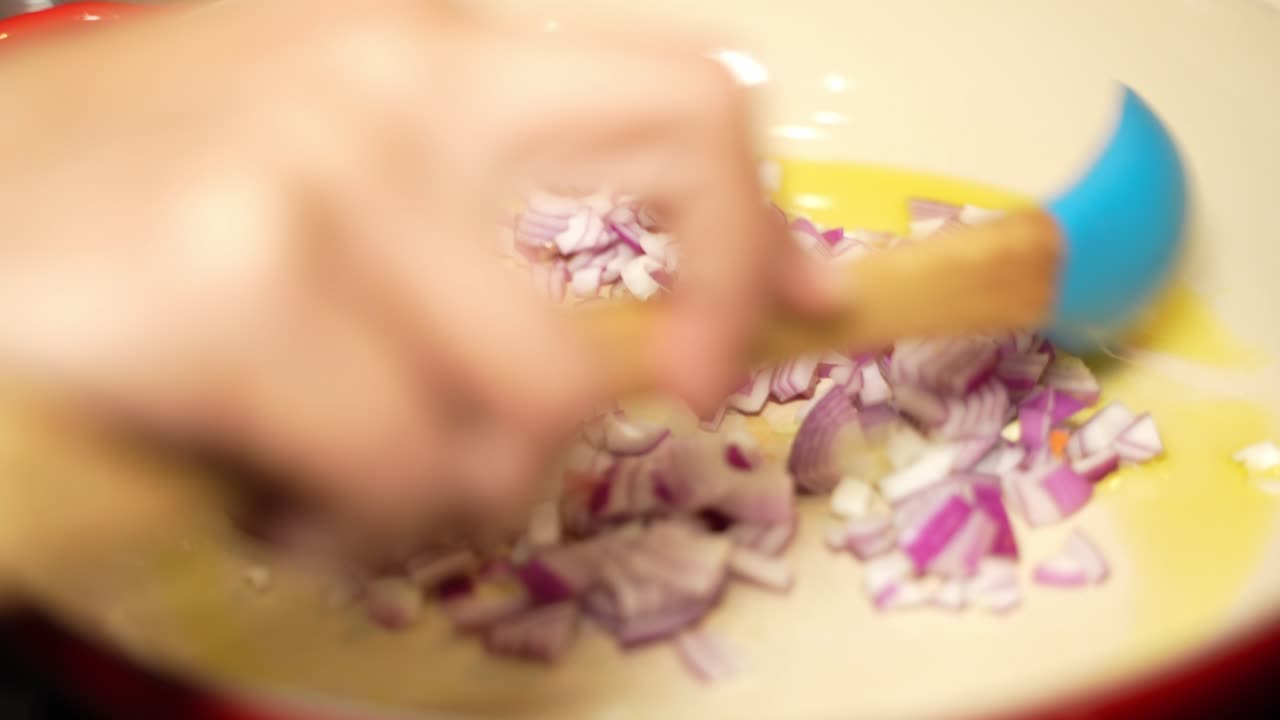 Closeup view of chopped onion getting fried on pan with oil.