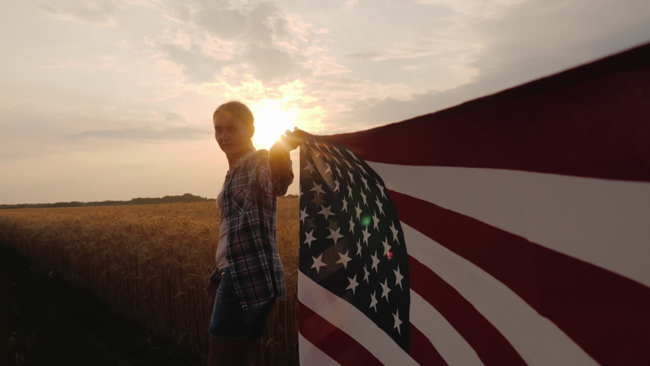 vista en primera persona de una mujer que lleva la bandera de estados unidos en uno de los bordes, acérquese al campo de trigo en su