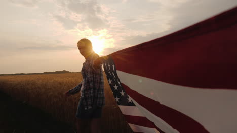 vista en primera persona de una mujer que lleva la bandera de estados unidos en uno de los bordes, acérquese al campo de trigo en su