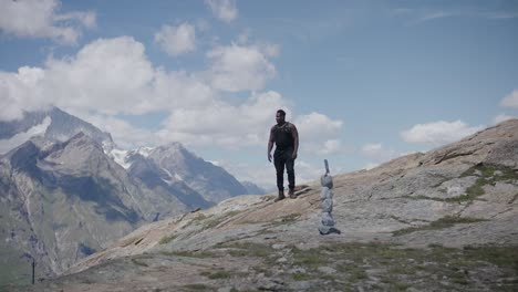 black male traveler with back pack looking around and walking up hill near matthorn in switzerland