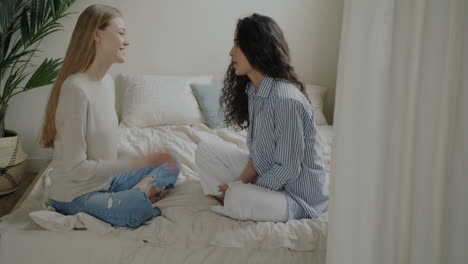 two women friends talking on a bed