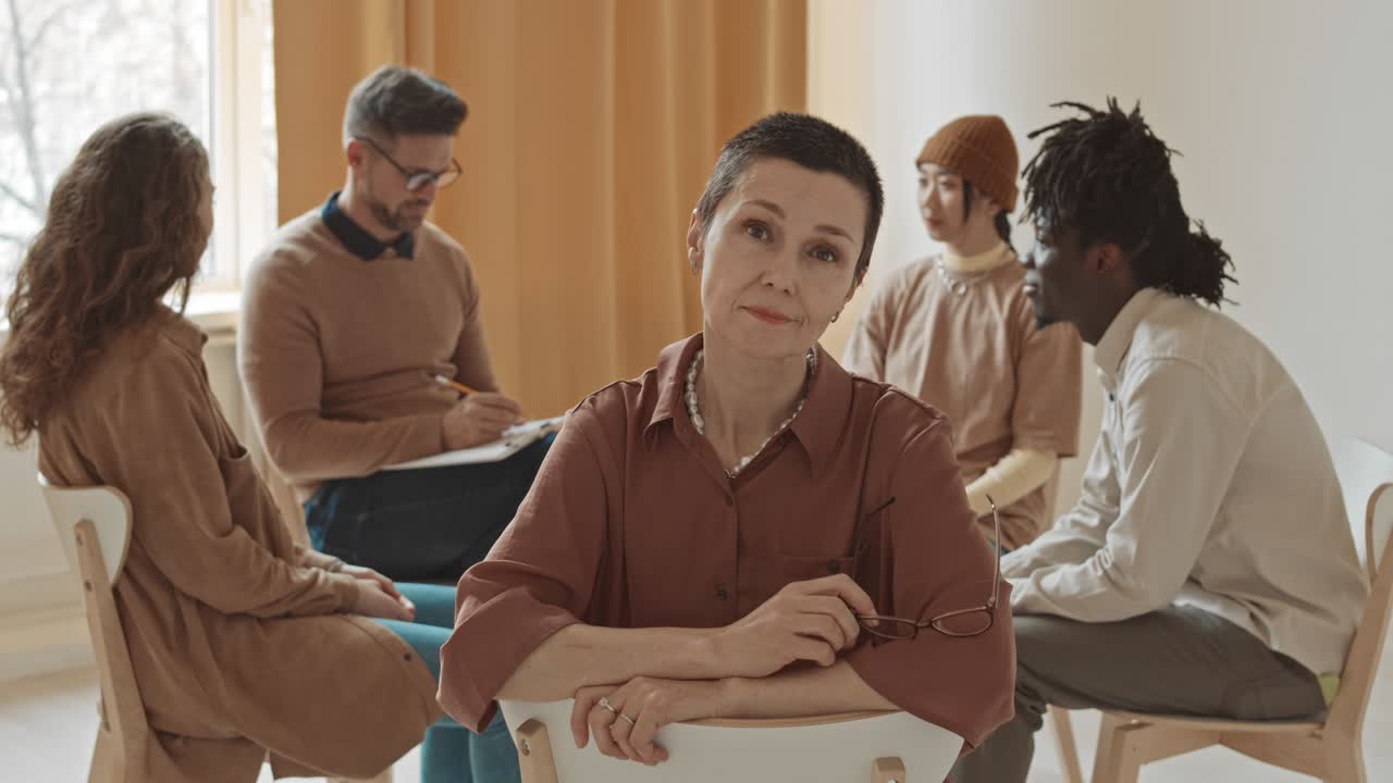 retrato de una mujer seria con gafas en una sesión de terapia de grupo
