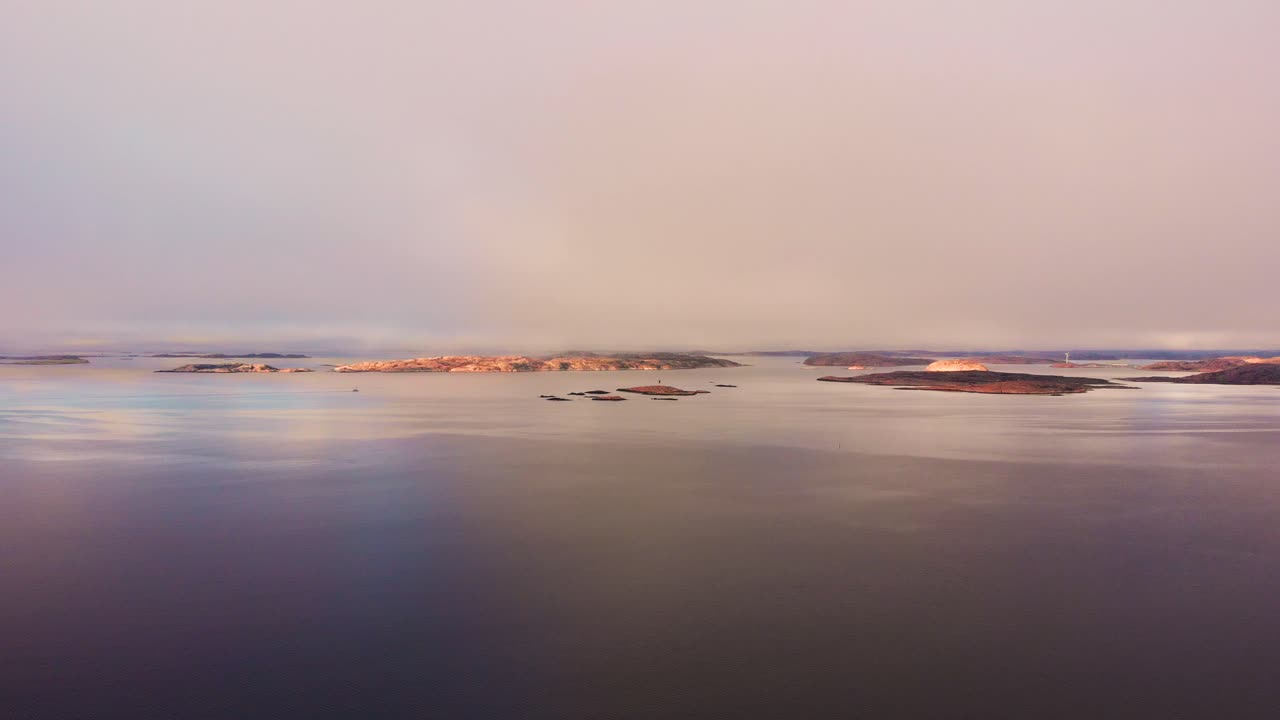The beautiful, peaceful and calm waters of Lysekil, Sweden with many small islands in the background during the purple sunset - Aerial shot
