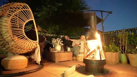 family nighttime relaxing scene, firepit illumination, garden furniture