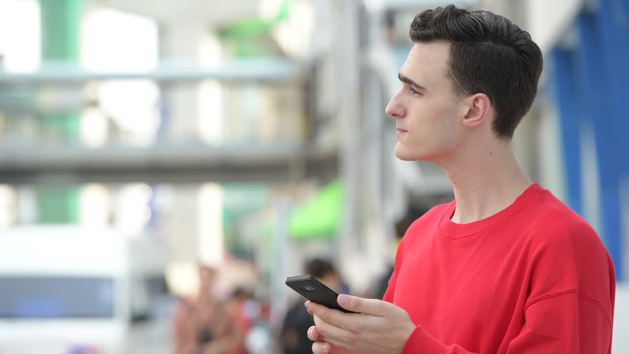 젊은 잘생긴 남자가 전화를 하면서 생각하고 있습니다.