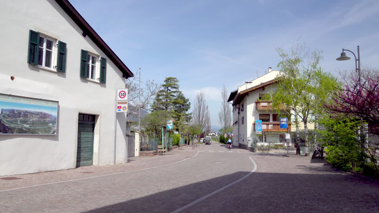 Cyclist,Tractor and cars on main road leading in and out of the village of Kurtinig - Cortina, South Tyrol, Italy (part 1of 3)